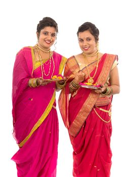 Portrait of Indian Traditional Girls holding diya and flower thali, Sisters celebrating Diwali or deepavali holding oil lamp during festival on white background