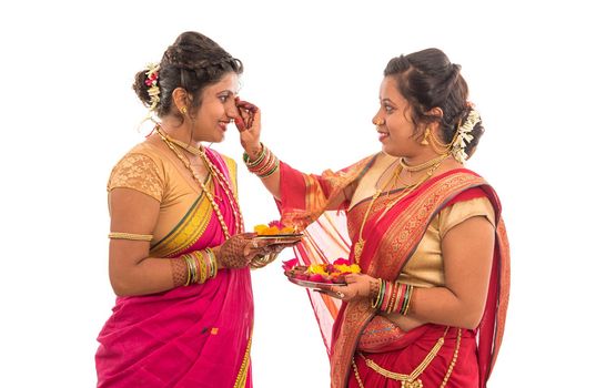 Portrait of Indian Traditional Girls holding diya and flower thali, Sisters celebrating Diwali or deepavali holding oil lamp during festival on white background