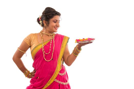 Portrait of a Indian Traditional Girl holding pooja thali with diya during festival of light on white background, Diwali or deepavali