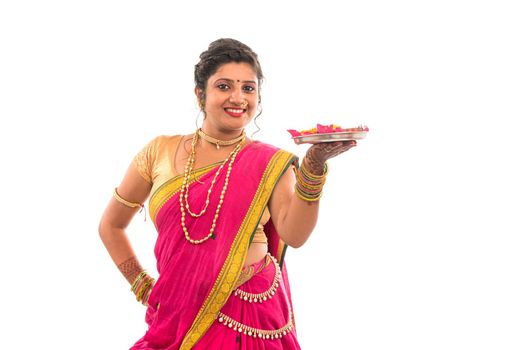 Portrait of a Indian Traditional Girl holding pooja thali with diya during festival of light on white background, Diwali or deepavali