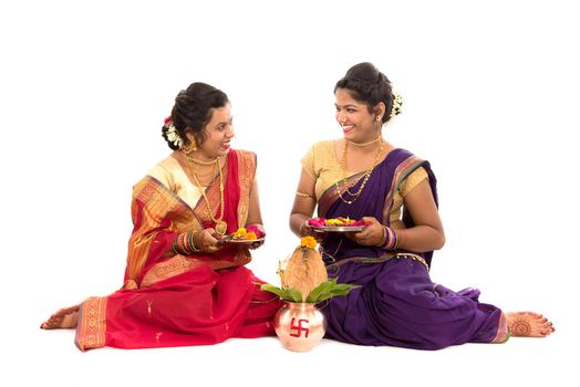 Indian Traditional Sisters performing worship, Indian Festival, copper kalash with coconut and mango leaf with floral decoration, essential in hindu puja.