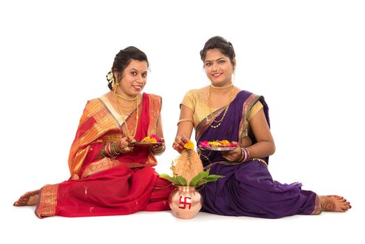 Indian Traditional Sisters performing worship, Indian Festival, copper kalash with coconut and mango leaf with floral decoration, essential in hindu puja.