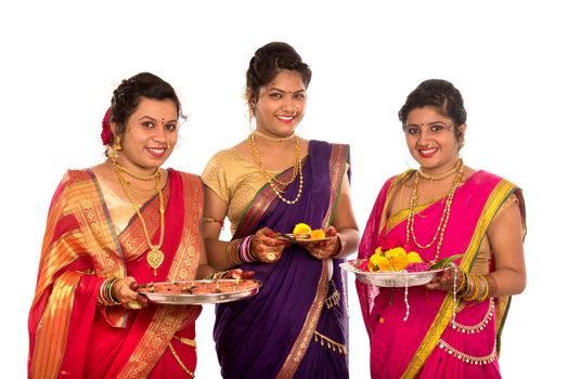 Portrait of Indian Traditional Girls holding diya and flower thali, Sisters celebrating Diwali or deepavali holding oil lamp during festival on white background