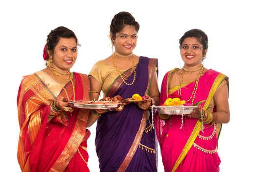 Portrait of Indian Traditional Girls holding diya and flower thali, Sisters celebrating Diwali or deepavali holding oil lamp during festival on white background