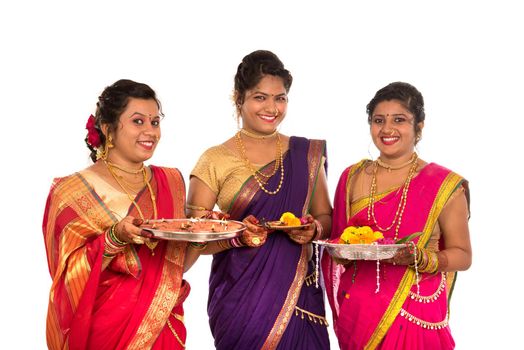 Portrait of Indian Traditional Girls holding diya and flower thali, Sisters celebrating Diwali or deepavali holding oil lamp during festival on white background