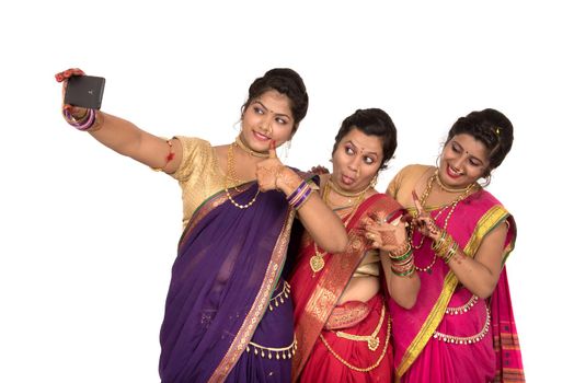 Indian traditional girls taking selfie with smartphone on white background