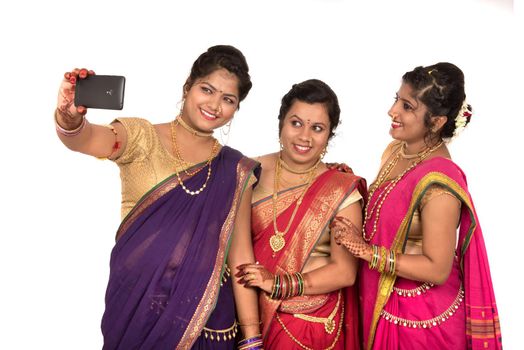 Indian traditional girls taking selfie with smartphone on white background