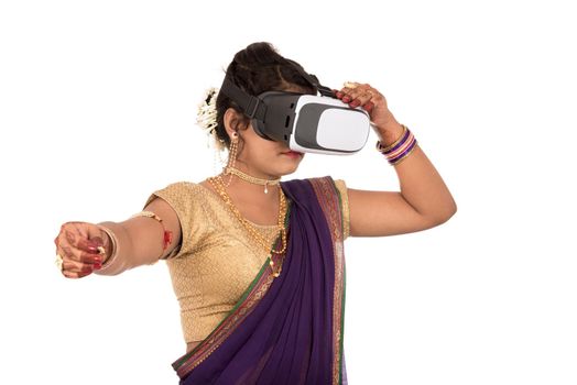 Indian traditional young woman in saree looking though VR device