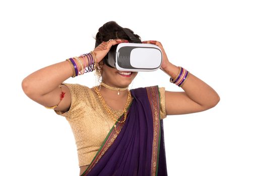 Indian traditional young woman in saree looking though VR device