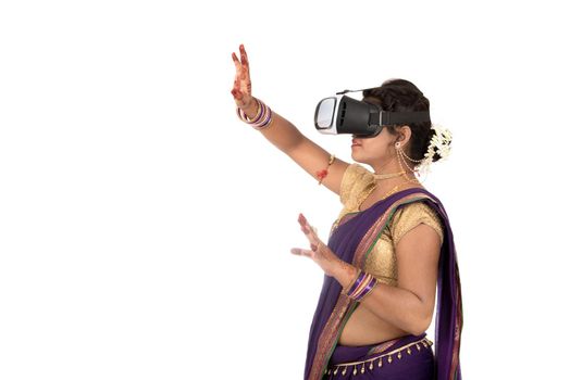 Indian traditional young woman in saree looking though VR device