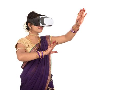 Indian traditional young woman in saree looking though VR device