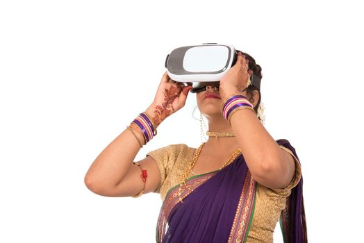 Indian traditional young woman in saree looking though VR device