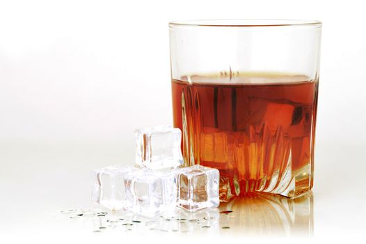 A cold glass of whiskey served with ice over a smoky grey and white background.