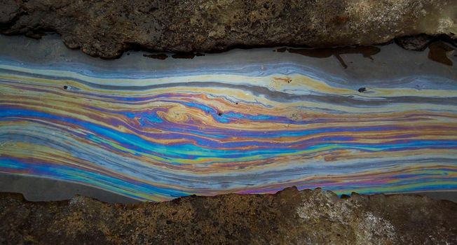 Color divorced from gasoline in the water of the river. Environmental pollution.