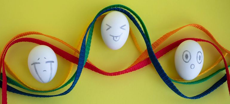 White eggs with funny faces on a yellow background. Easter Concept.