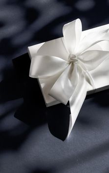 Anniversary celebration, shop sale promotion and luxe surprise concept - Luxury holiday white gift box with silk ribbon and bow on black background, luxe wedding or birthday present