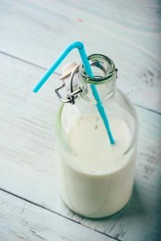 Milk in glass bottle with blue straw