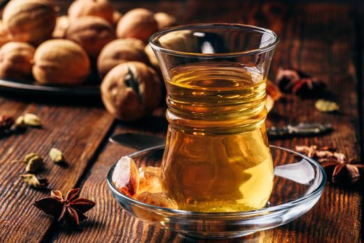 Arabic tea with star anise, cardamom and dried lime in oriental glass over wooden surface