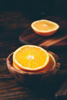 Sliced orange in a wooden bowl in rustic setting