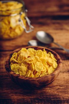 Corn flakes in a wooden bowl on rustic surface