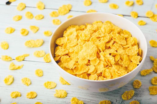 White bowl of corn flakes on a wooden surface