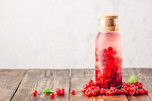 Red currant infused water with ice in glass bottle