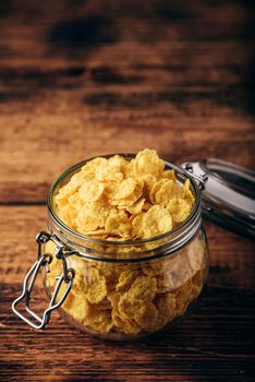 Corn flakes in a glass jar on wooden surface