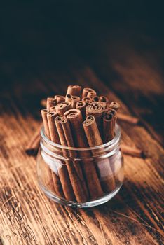 Cinnamon sticks in a glass jar over rustic wooden surface