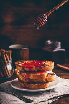 Stack of french toasts with berry syrup on white plate