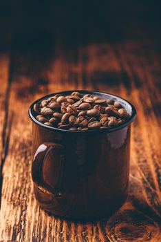 Metal mug full of roasted coffee beans