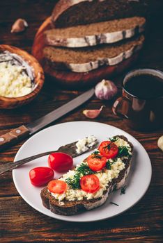 Rye bread toast with processed cheese, garlic and sliced cherry tomatoes