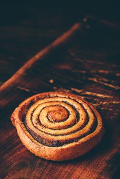 Sweet roll with poppy seeds on rustic wooden surface