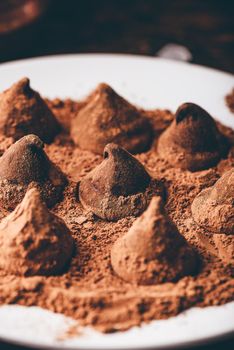 Homemade chocolate truffles coated in cocoa powder on white plate