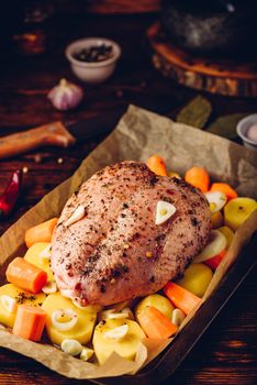 Seasoned chicken breast with carrot and potato ready for roast in oven