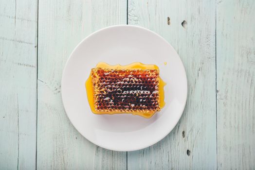 Top view of delicious yummy honeycomb on bright plate over light wooden background