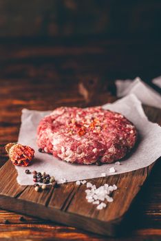 Raw Pork Patty with Spices on Cutting Board for Burger. Vertical Orientation and Copy Space.