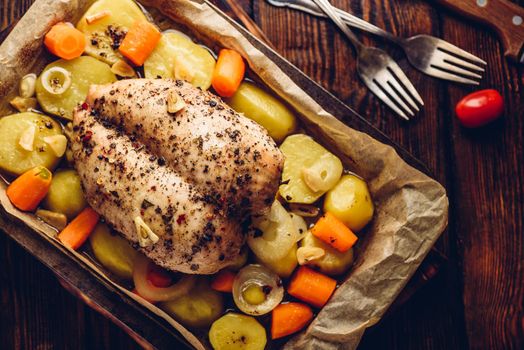 Seasoned chicken breast baked in oven with vegetables on baking sheet