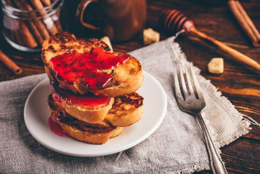 Stack of french toasts with berry marmalade on white plate