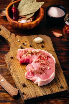 Pork loin steak with ground spices on cutting board