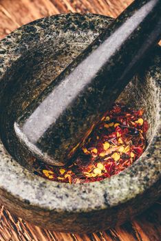 Red chili pepper grinded in mortar. High angle view