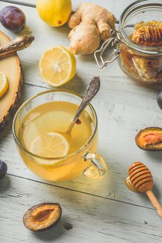 Cup of tea with lemon, honey and ginger over wooden surface
