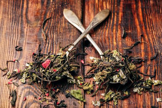 Two spoonfuls of raspberry herbal tea over wooden surface