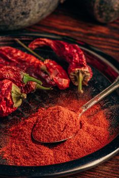 Spoonful of ground chili pepper with dried fruits on metal plate