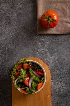Tomatoes in salad inside a white bowl on grayish background
