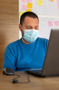 Young man with medical mask working with his laptop