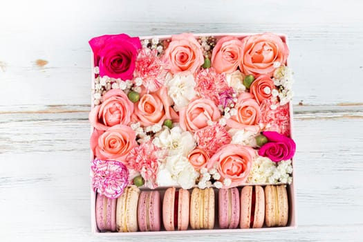 Floral arrangement of pink roses with macarons of different colors