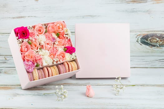 Floral arrangement of pink roses with macarons of different colors