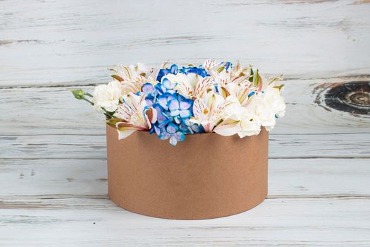 Floral arrangement with blue hydrangeas in recyclable cardboard box