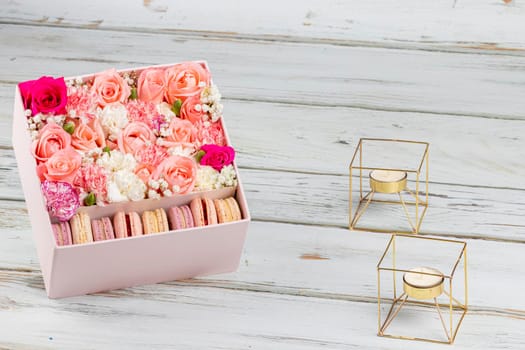Floral arrangement of pink roses with macarons of different colors