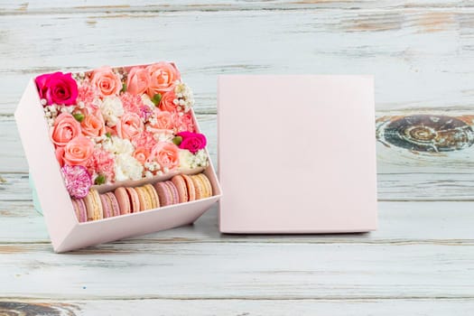 Floral arrangement of pink roses with macarons of different colors